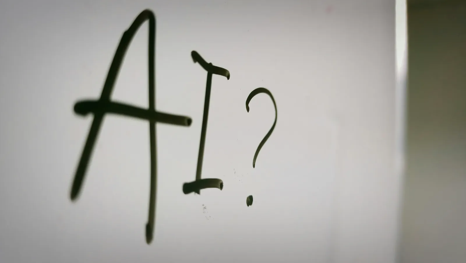 The letters A I and a question mark handwritten on a whiteboard