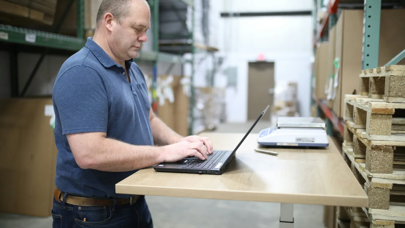 A small business owner working on a laptop in his distribution warehouse